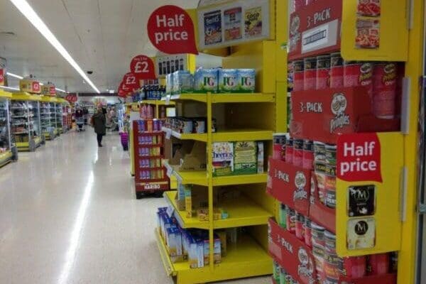 Tesco supermarket aisle with red pricing tags on yellow shelves