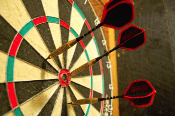 Black and white Dartboard with three red darts in the centre