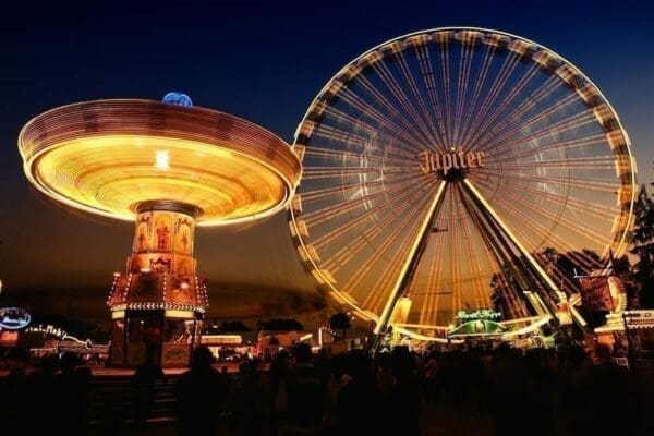 Lit up fair rides at night with a crowd at the front