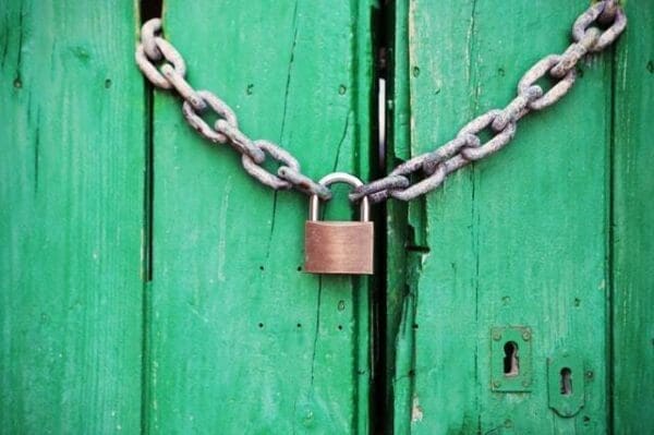 Metal padlock and chain on the front of green wooden door