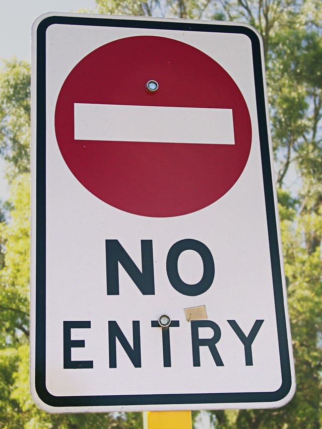Red No Entry Stop Sign with green trees in the background