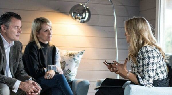 Female communication coach talks to an older couple on a sofa opposite each other