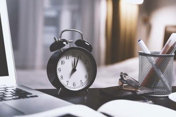 Alarm clock on a desk with laptop pen cup