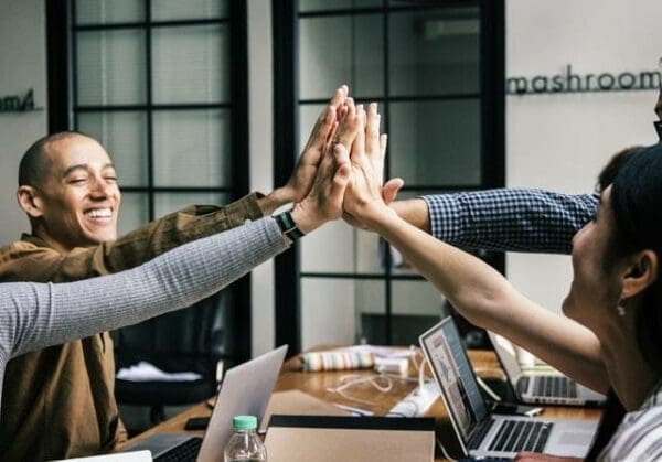 Employees engaging in a group high 5 over a table