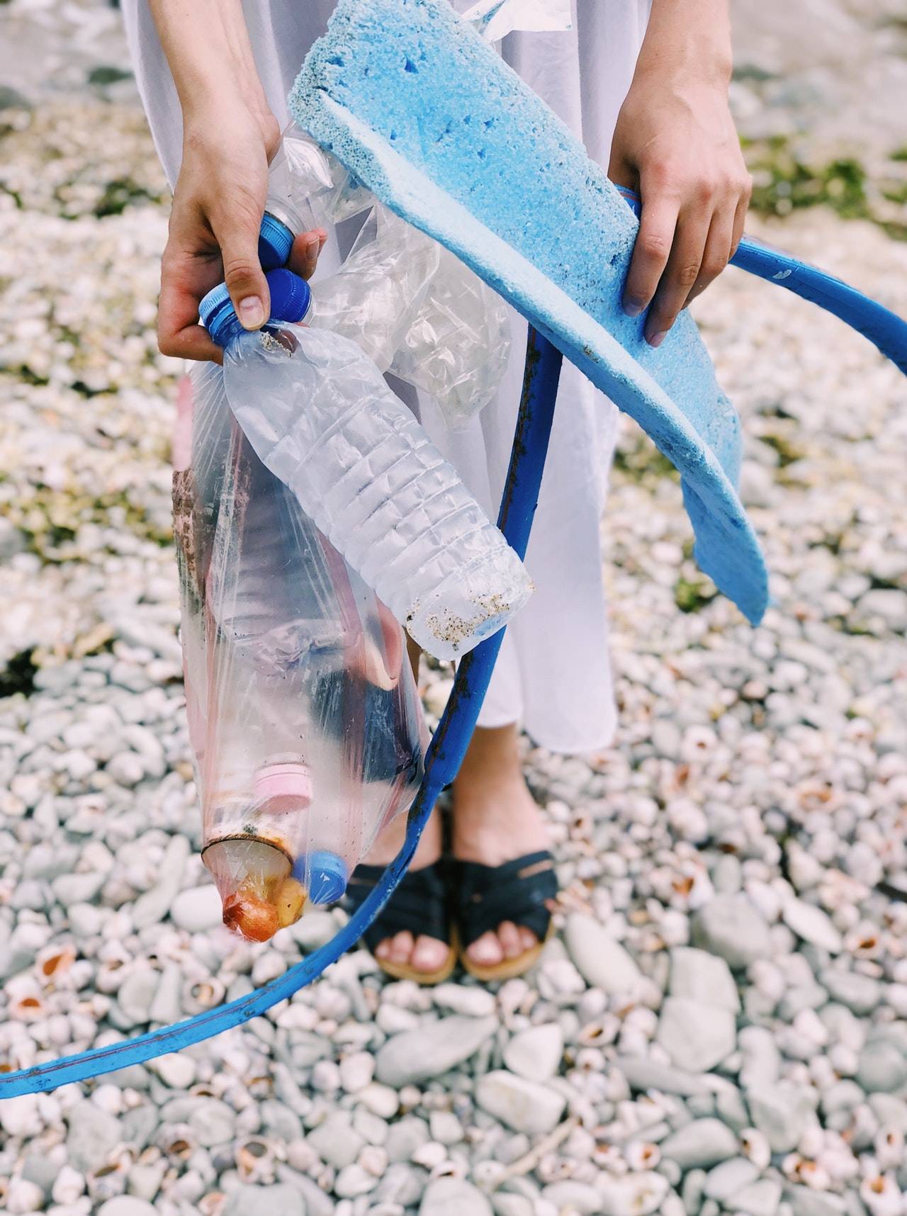 washed-up plastic rubbish on a beach Person holds out washed-up plastic rubbish on a beach