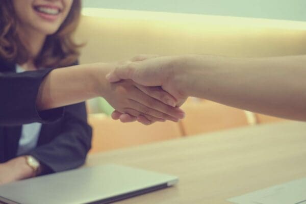 Female leader shaking hands with someone over a laptop