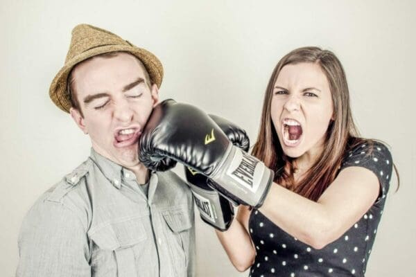 Angry woman punching a man with boxing gloves on represents physical conflict