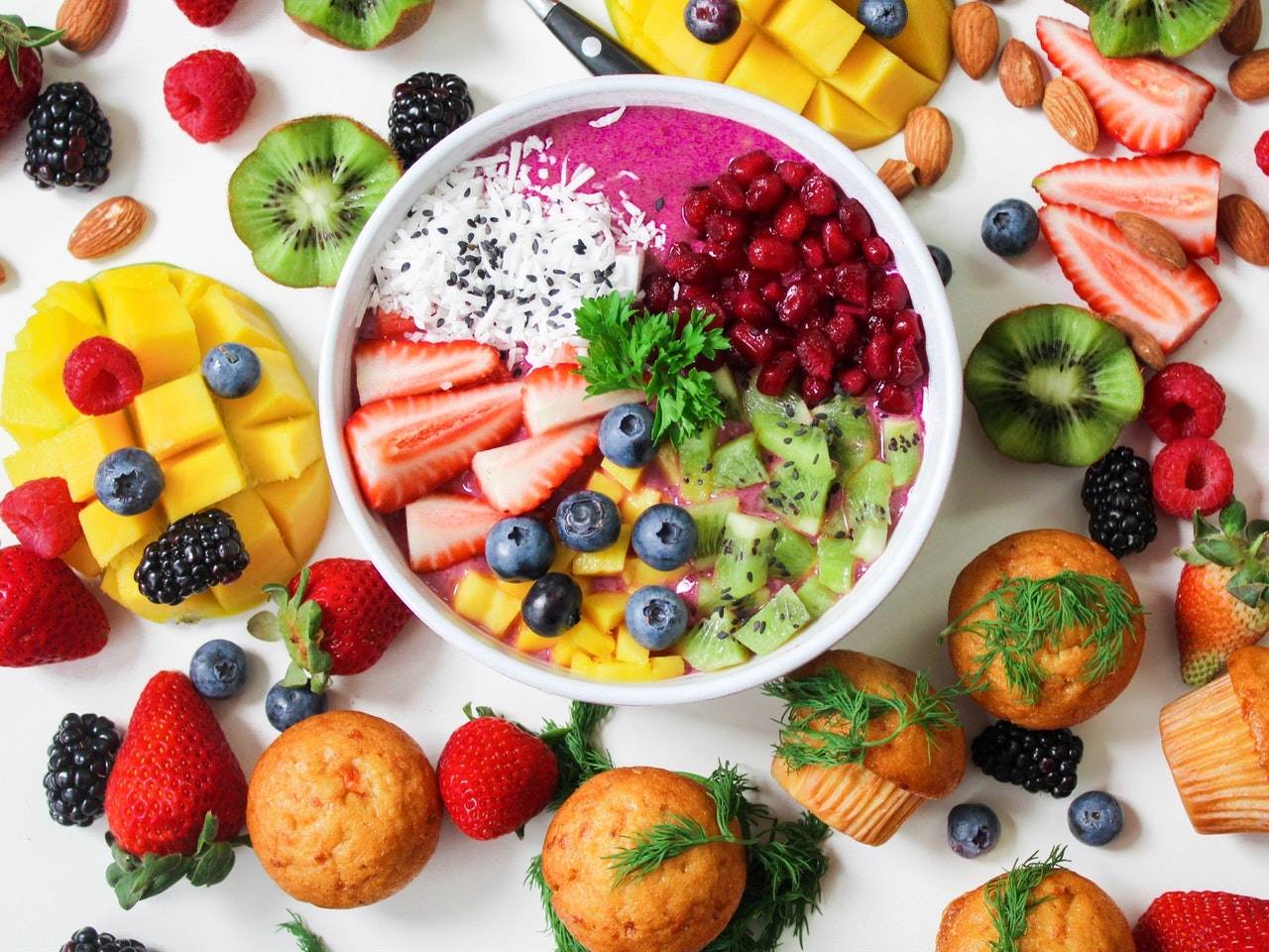 Decorative breakfast fruit bowl Decorative fruit bowl with muffins, pineaple, and berries around it