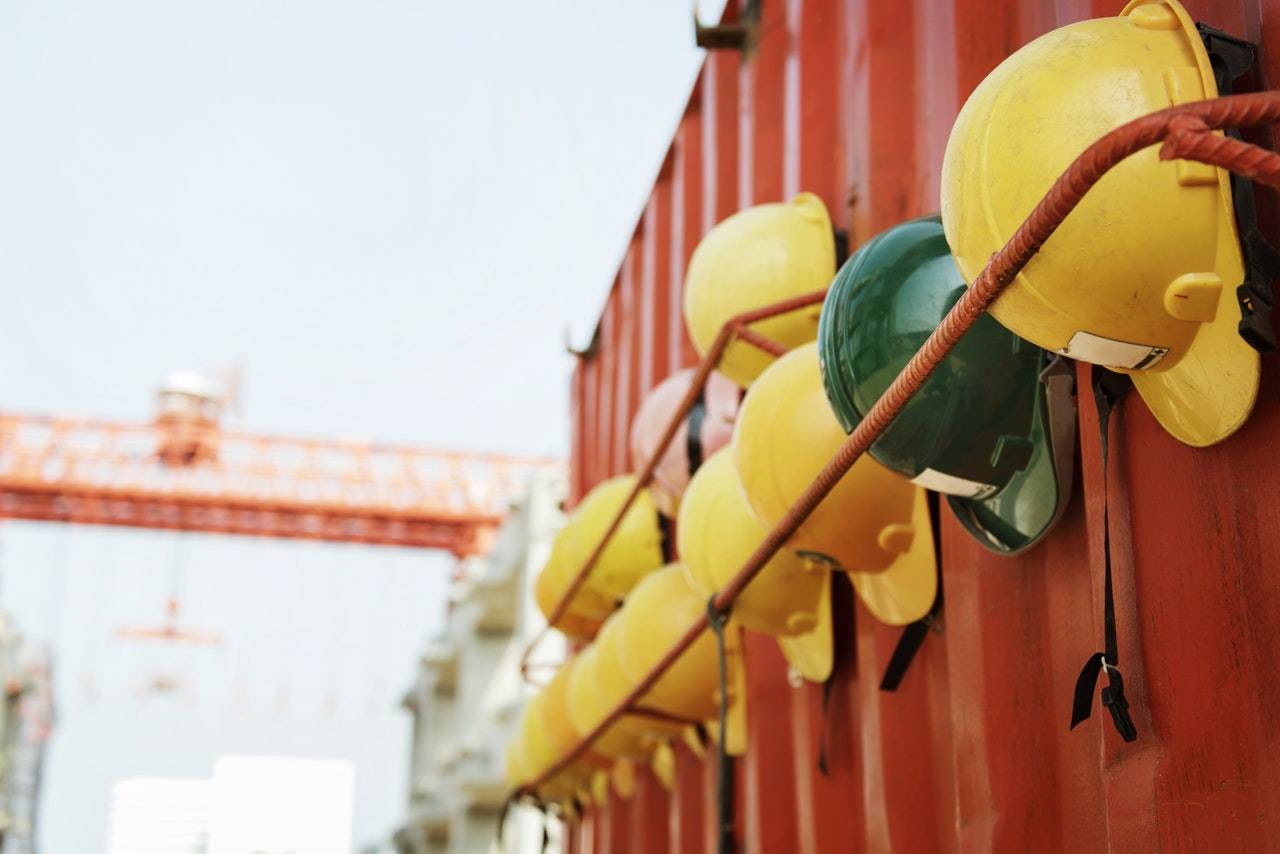 Construction helmets hanging in a line Line of safety helmets hanging from the side of a metal shipping container.