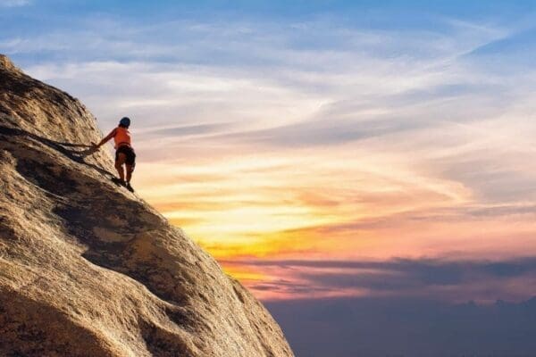 Woman rock climbing whilst the sun sets represents courage