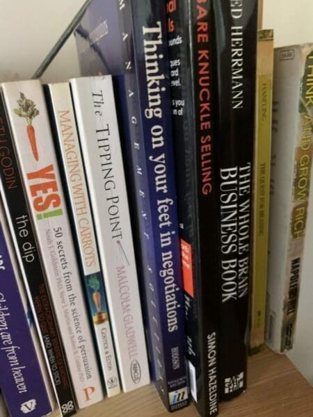 Spines of several negotiation and self-improvement books on a book shelf