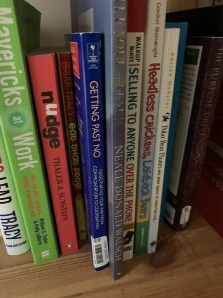 Spines of several negotiation and self-improvement books on a book shelf