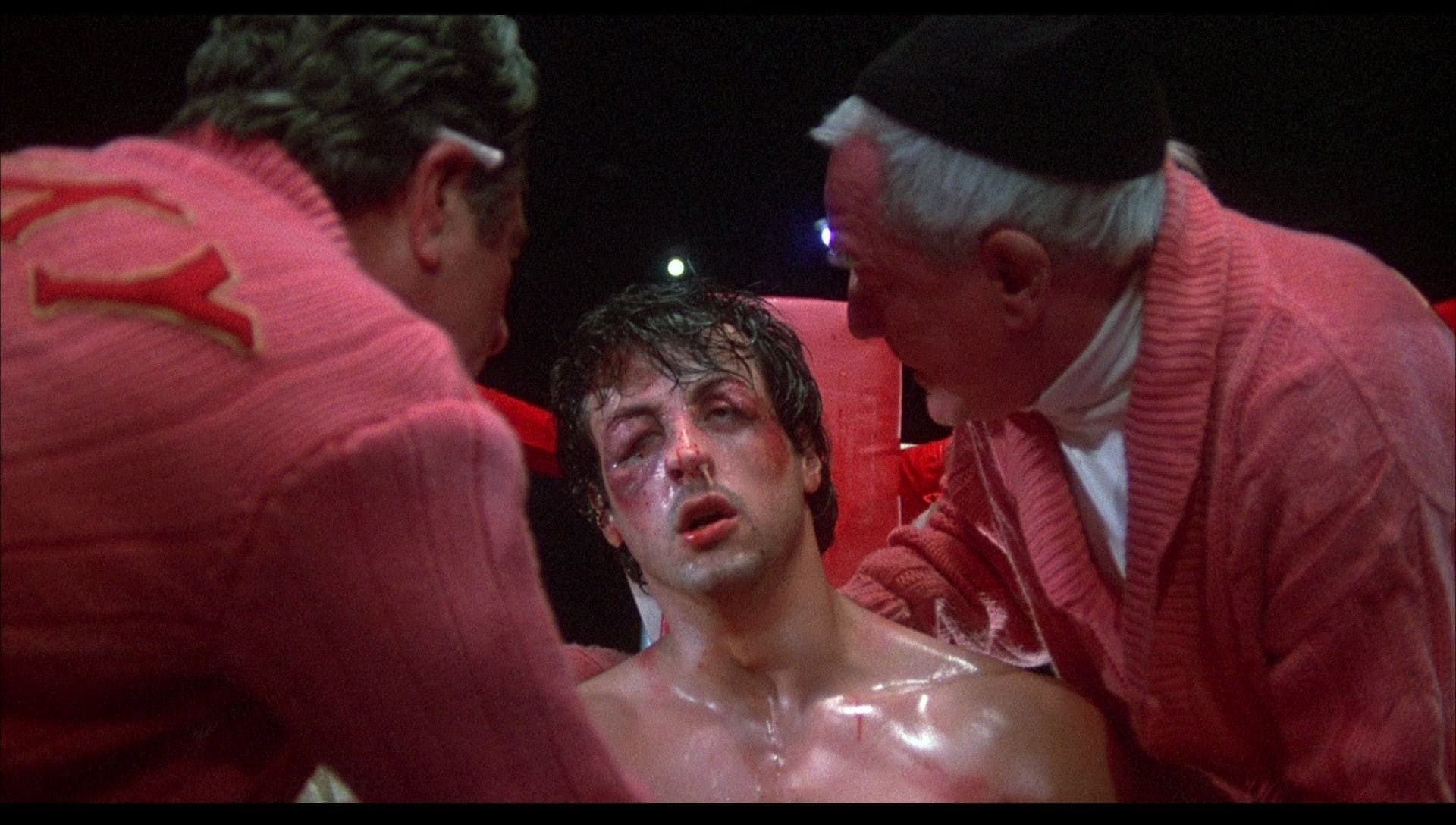 Rocky sitting down all beat up at the ringside while being coached