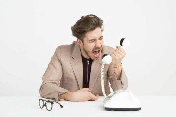 Angry businessman shouting into the phone to deal with stress
