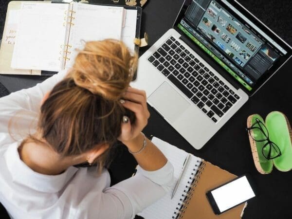 Woman having a headache over multiple tasks in front for her with bad emotional wellbeing