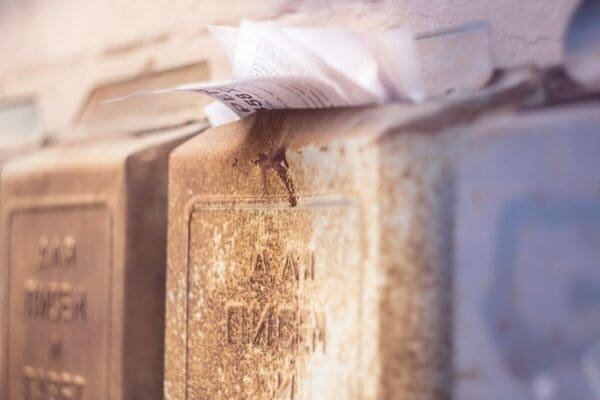 rusty postbox overflowing with mail