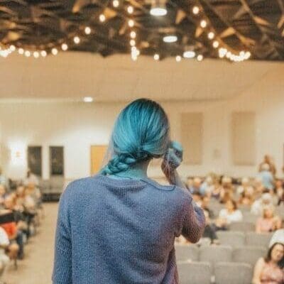 Back of a woman presenting to an audience from a stage