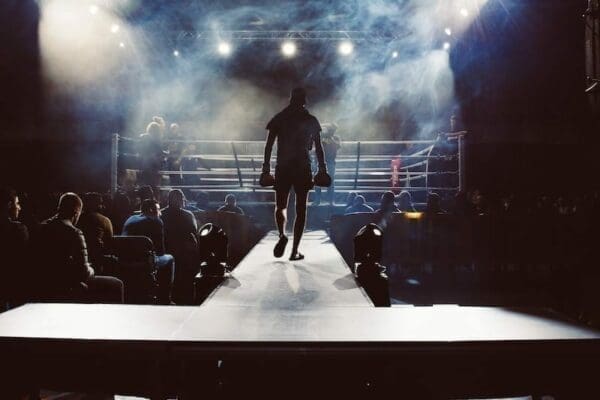 Silhouette of a boxer entering a boxing ring with an audience