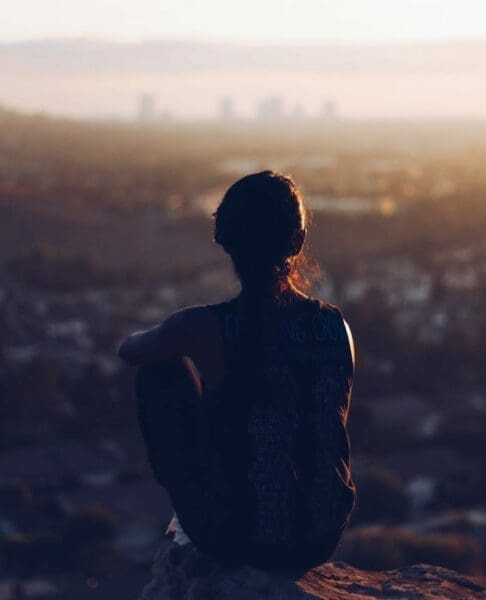 Clarity Person sitting on cliff looking out over a city