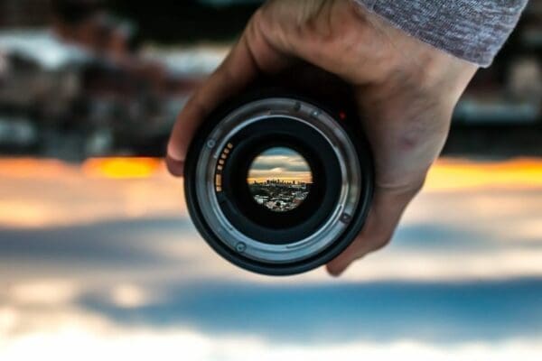 Man holding a lens showing a reverse image of the background