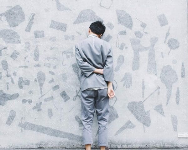 Shy man facing the wall with his left hand holding his right arm