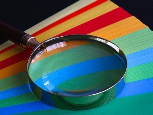 Magnifying glass on top of multi coloured papers