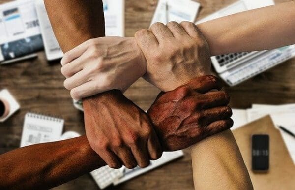 Four team member hands holding each other's wrists in a square