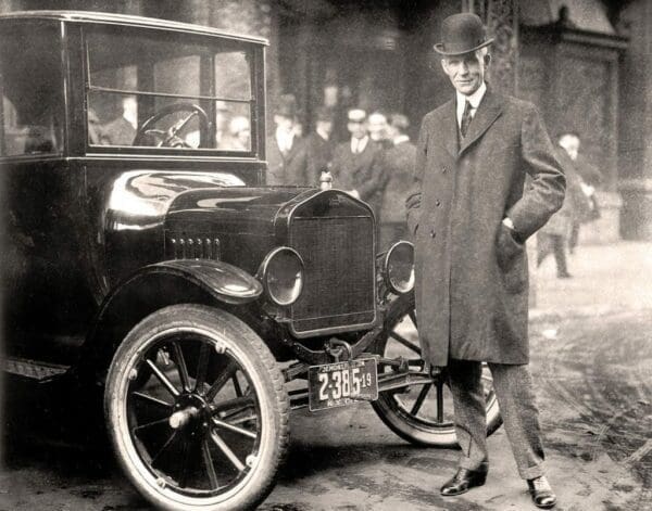 Henry Ford and vehicle Black and white photo Henry Ford 1921 in suit beside a classic car in the middle of the street
