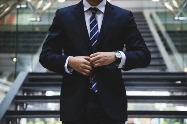 Man in suit and tie, buttoning his jacket