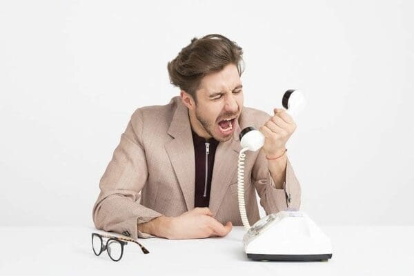 Businessman at a table yelling through a telephone
