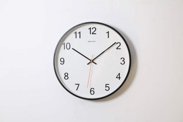 Clock mounted on a white wall with time showing 10:10 represents time management