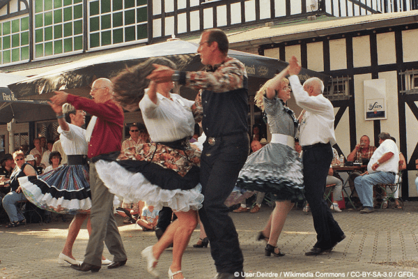 Group of old couples dancing in pairs outside a pub