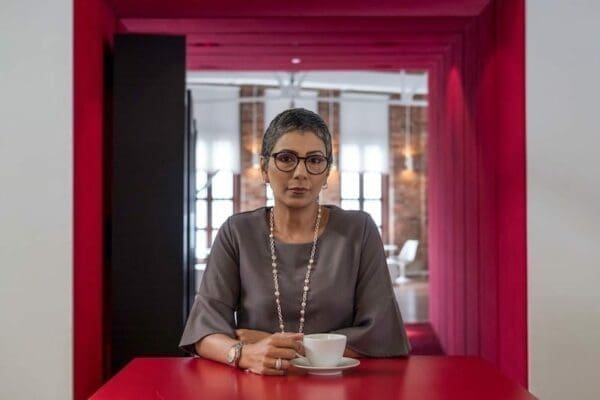 Woman at red table with a teacup is practicing self-care