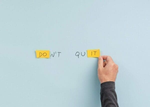 Don't Quit written on the wall with two sticky notes at either end represents determination