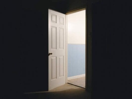A dark room with an open door and light coming through represents opportunity