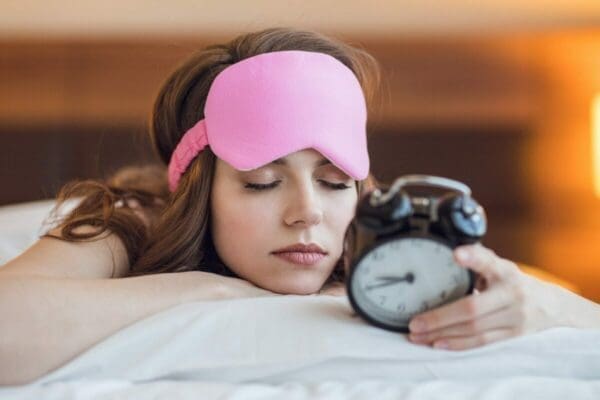 Sleeping young girl with a clock practices time management