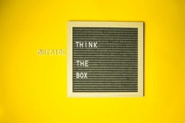 Think outside the box quote with air vent and yellow wall background