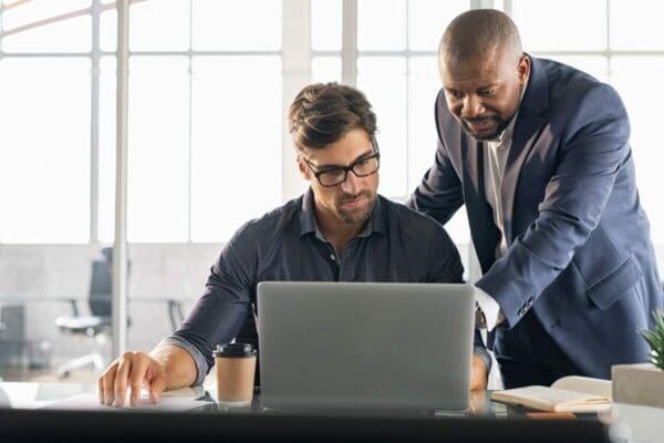 Leader uses great communication as he shows a coworker something on a laptop