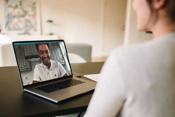 Two coworkers having a video call on a laptop to build rapport virtually