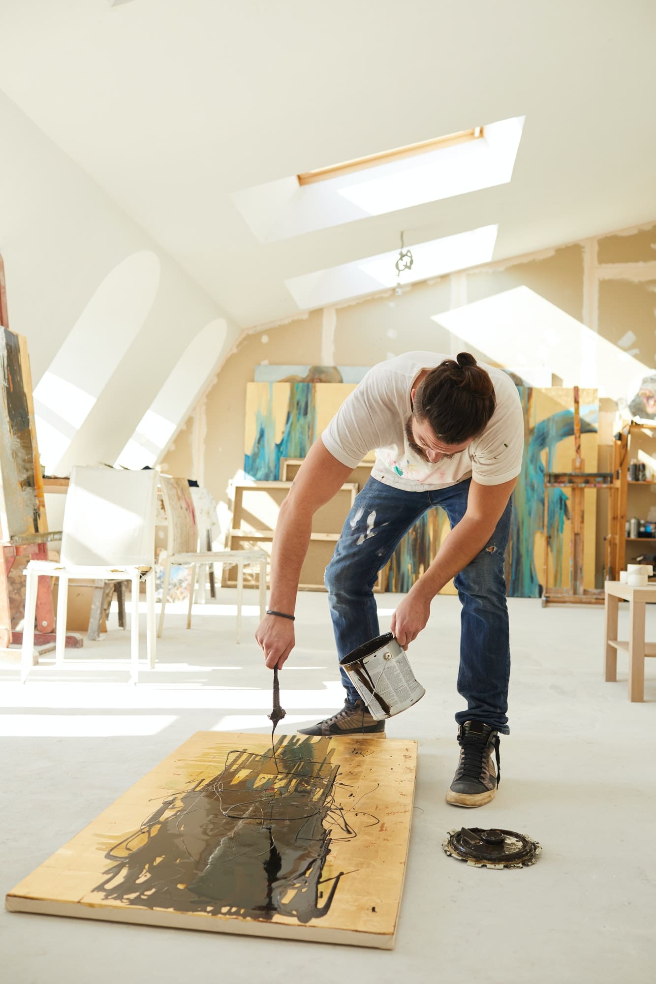 A man painting a wooden board A man painting a wooden board with paint on his clothes