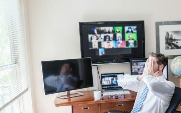 Man in a team video call has his hands over his face 