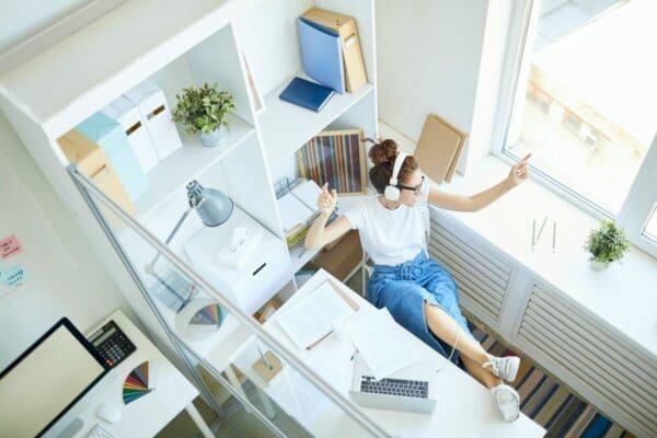 Woman working from home is distracted by listening to music through her headphones