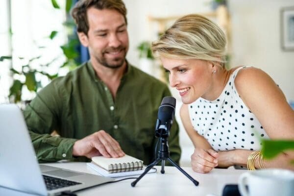 Happy couple with a microphone is having a video call on a laptop indoors at home