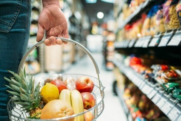 Fruit basket held by a male customer in a supermarket isle