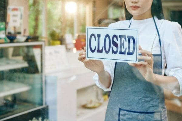 Woman in an apron turning the cafe sign to closed 