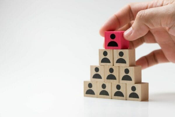 Hand putting red leader cube on top of pyramid of employees