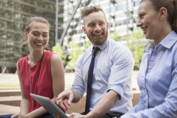 Three co-workers seated outside working and looking happy