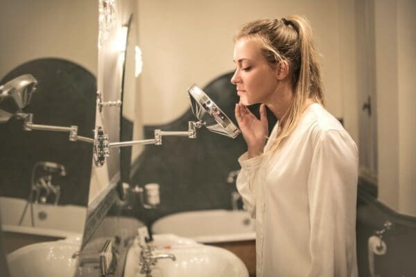 A woman pampering herself in front of a shaving mirror to become less nervous