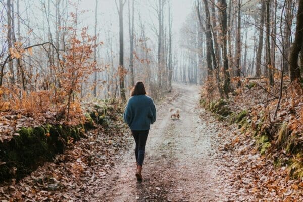 Woman walking her dog among trees to become less nervous