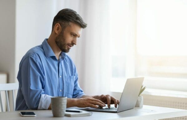 Male businessman responding to emails on his laptop